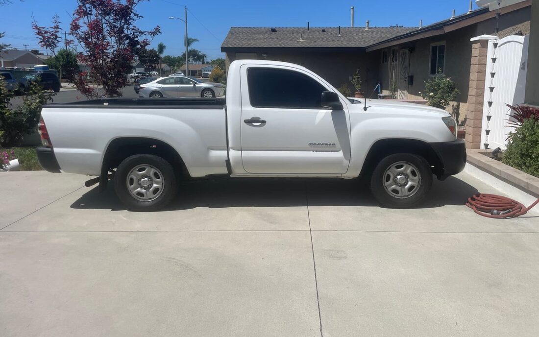 An old white single-cab Toyota Tacoma pickup truck